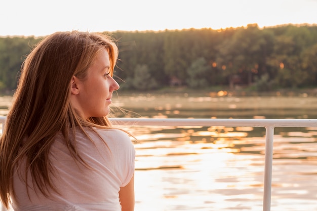 Foto gratuita hermosa mujer joven en ropa blanca sentado en la orilla del río en