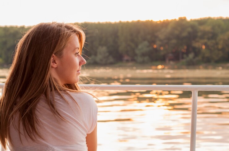 Hermosa mujer joven en ropa blanca sentado en la orilla del río en
