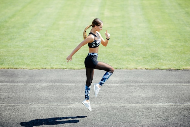 Hermosa mujer joven en ropa deportiva calentamiento con ejercicios de salto mientras hace ejercicio al aire libre.