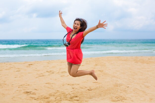 Hermosa mujer joven saltando en la playa