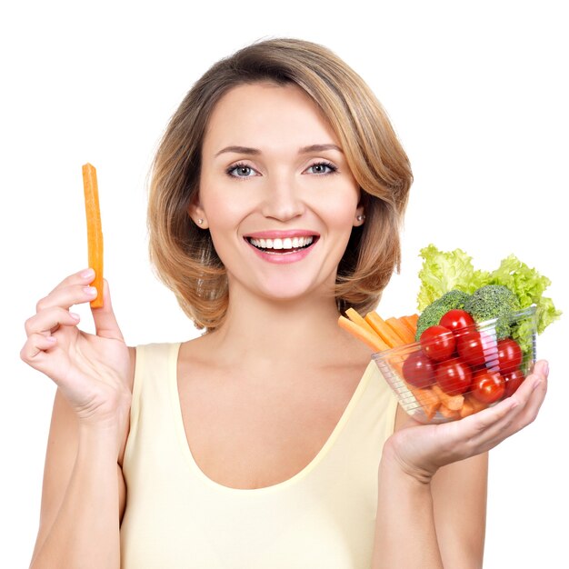 Hermosa mujer joven sana con un plato de verduras aislado en blanco.