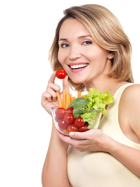 Hermosa mujer joven sana con un plato de verduras aislado en blanco.