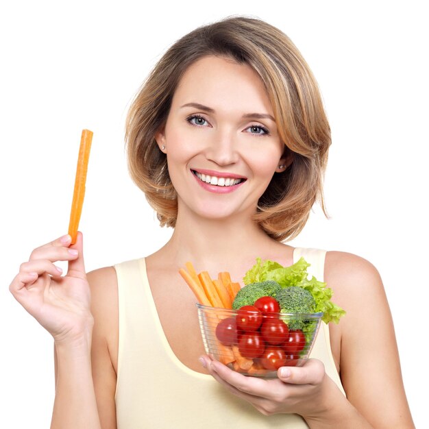 Hermosa mujer joven y sana con un plato de verduras - aislado en blanco.