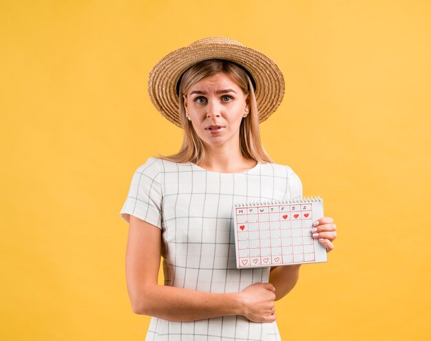 Hermosa mujer joven con sombrero con dolor de estómago