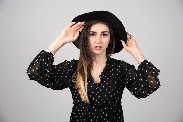 Hermosa mujer joven con sombrero negro mirando a la cámara.