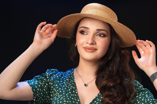 Hermosa mujer joven con sombrero de paja posando sobre fondo negro