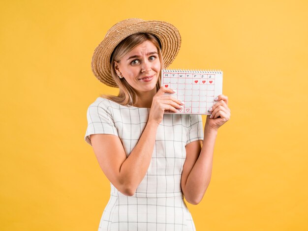 Hermosa mujer joven con sombrero sosteniendo un calendario de época