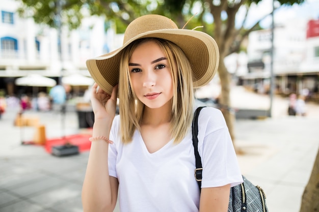 Hermosa mujer joven con sombrero de verano caminando en la ciudad.