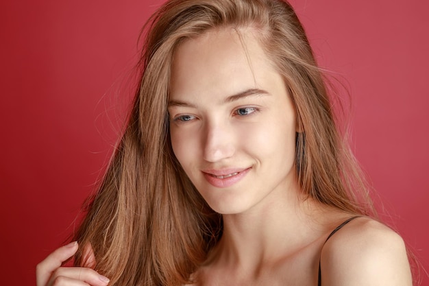 Hermosa mujer joven sonriente con el concepto de belleza natural de la cara de la piel perfecta aislada en el fondo del estudio