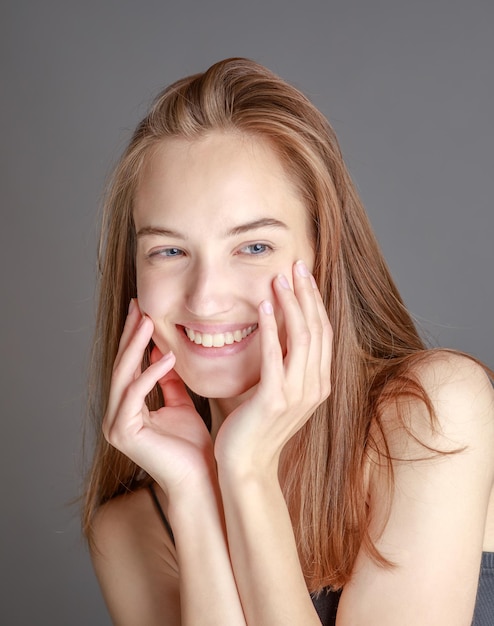 Hermosa mujer joven sonriente con el concepto de belleza natural de la cara de la piel perfecta aislada en el fondo del estudio