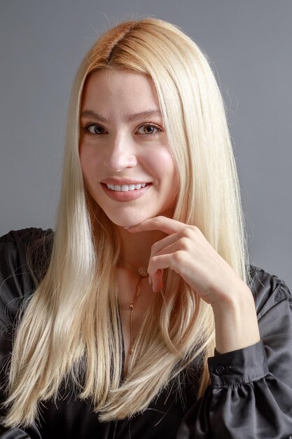 Hermosa mujer joven sonriente con el concepto de belleza natural de la cara de la piel perfecta aislada en el fondo gris del estudio