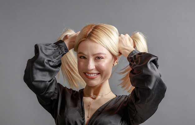 Hermosa mujer joven sonriente con el concepto de belleza natural de la cara de la piel perfecta aislada en el fondo gris del estudio