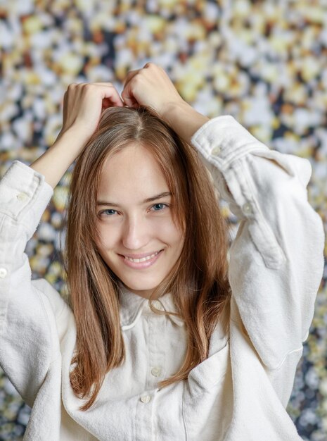 Hermosa mujer joven sonriente con el concepto de belleza natural de la cara de la piel perfecta aislada en el fondo gris del estudio