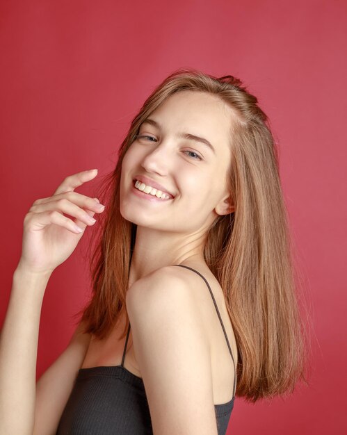 Hermosa mujer joven sonriente con el concepto de belleza natural de la cara de la piel perfecta aislada en el fondo gris del estudio