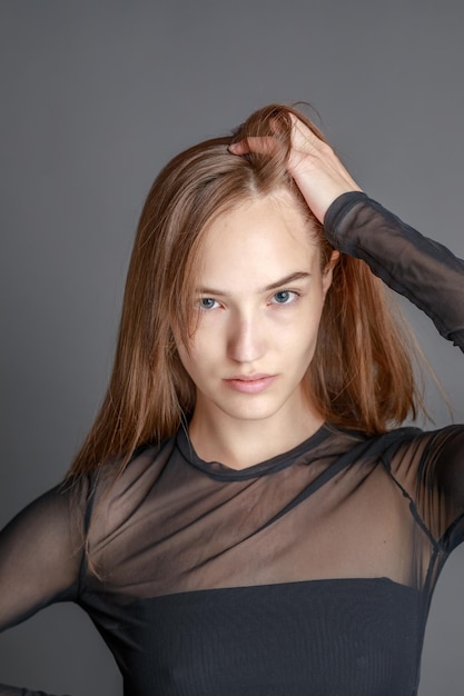 Hermosa mujer joven sonriente con el concepto de belleza natural de la cara de la piel perfecta aislada en el fondo gris del estudio