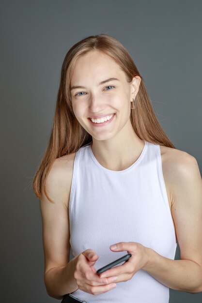 Hermosa mujer joven sonriente con el concepto de belleza natural de la cara de la piel perfecta aislada en el fondo gris del estudio