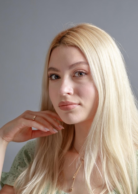 Hermosa mujer joven sonriente con el concepto de belleza natural de la cara de la piel perfecta aislada en el fondo gris del estudio