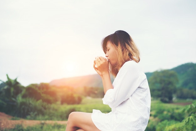 Hermosa mujer joven sosteniendo una taza de café que se sienta en el