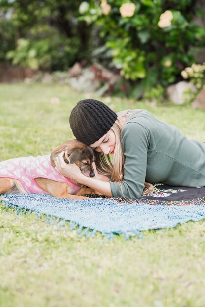 Hermosa mujer joven su perro acostado relajante en el parque