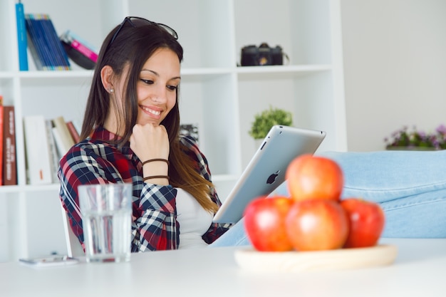 Hermosa mujer joven con su tableta digital en casa.