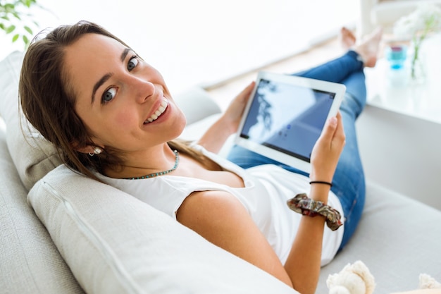 Hermosa mujer joven con su tableta digital en casa.