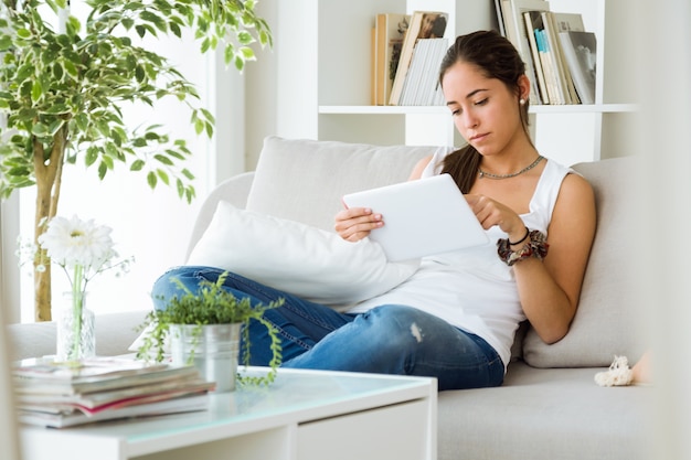 Hermosa mujer joven con su tableta digital en casa.