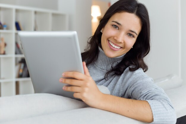 Hermosa mujer joven con su tableta digital en casa.