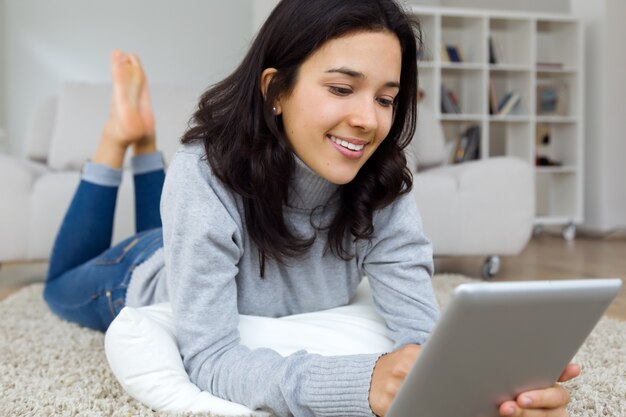 Hermosa mujer joven con su tableta digital en casa.