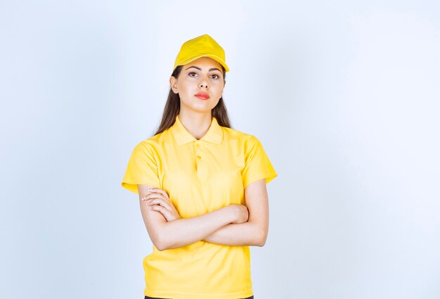 Hermosa mujer joven en traje amarillo de pie y mirando en blanco.