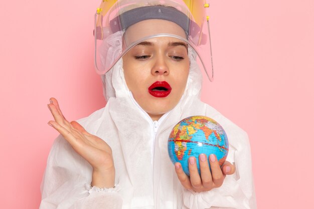 Hermosa mujer joven en traje blanco especial y casco amarillo sosteniendo un pequeño globo en rosa