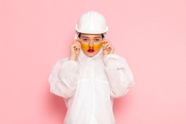 Hermosa mujer joven en traje blanco especial con casco protector posando fresco en rosa