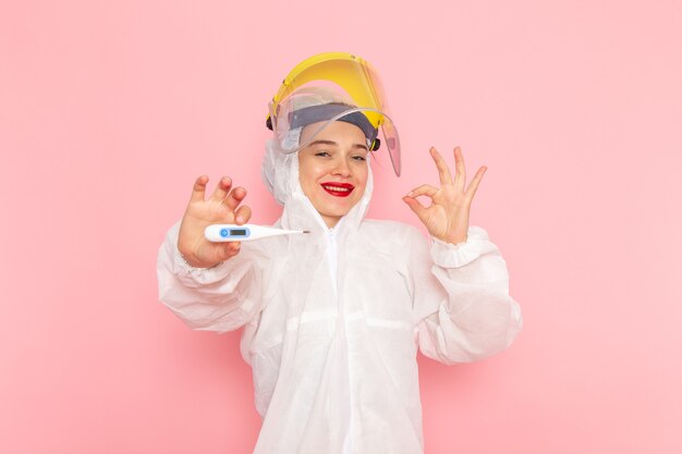 Hermosa mujer joven en traje blanco especial con dispositivo de sujeción de casco protector con sonrisa en rosa