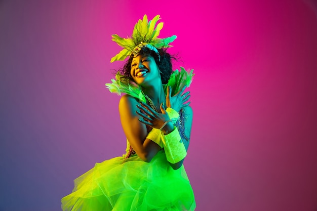 Foto gratuita hermosa mujer joven en traje de carnaval y mascarada en gradiente en luz de neón