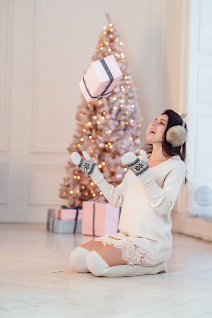 Hermosa mujer joven con un vestido blanco arroja un regalo