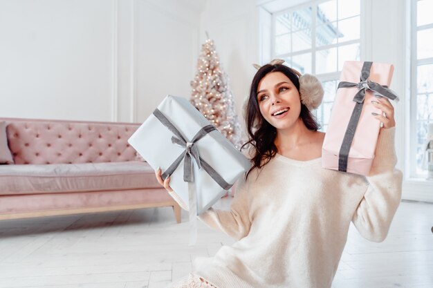 Hermosa mujer joven en vestido blanco posando con cajas de regalo