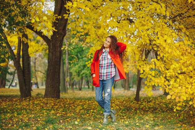 Hermosa mujer jugando con el pelo mientras camina en el parque otoño