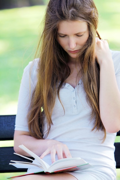 Hermosa mujer leyendo el libro en el parque