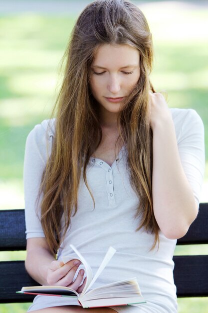 Hermosa mujer leyendo el libro en el parque