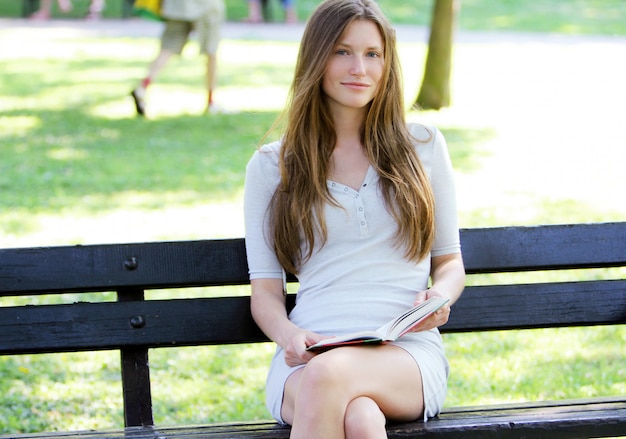 Hermosa mujer leyendo el libro en el parque