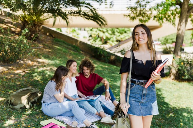 Hermosa mujer con libro en el parque con amigos