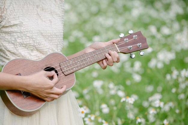 Hermosa mujer con un lindo vestido blanco y sosteniendo un ukelele