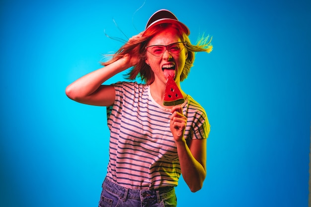 Hermosa mujer en luz de neón aislada en estudio azul