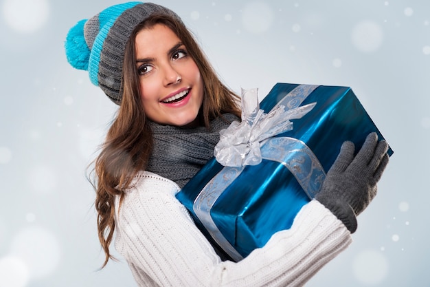 Hermosa mujer durante la mágica Navidad con regalo azul