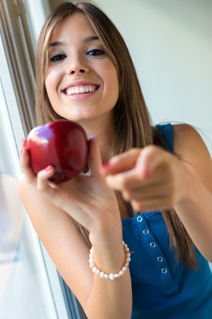 Hermosa mujer con manzana roja en casa.