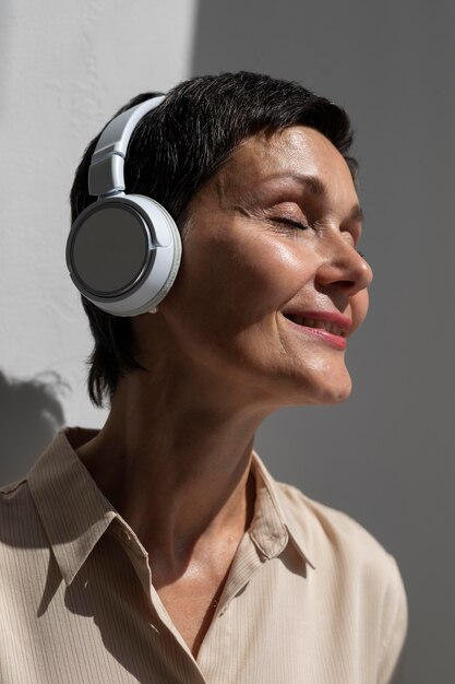 Hermosa mujer de mediana edad escuchando música a través de auriculares