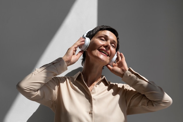 Foto gratuita hermosa mujer de mediana edad escuchando música a través de auriculares