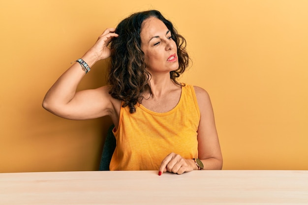 Foto gratuita hermosa mujer de mediana edad con ropa informal sentada en la mesa confundida y preguntándose sobre la pregunta incierta con dudas pensando con la mano en el concepto pensativo de la cabeza