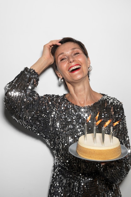 Hermosa mujer de mediana edad sosteniendo un pastel de cumpleaños
