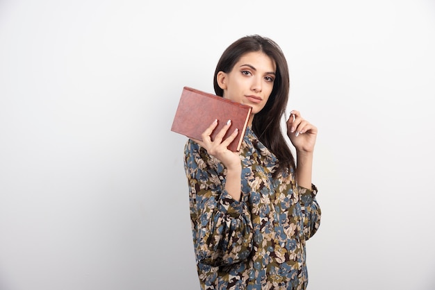 Hermosa mujer mirando a cámara con libro.