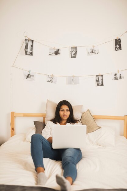 Hermosa mujer mirando en la computadora portátil en la cama